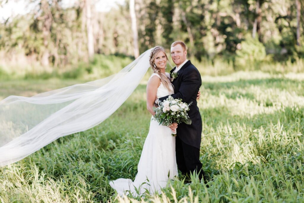 This bride requested an area of grass to be left high and uncut, specifically for photos like this one. The shadows, the color variations of the foliage and her veil lifting in the breeze combined for an unforgettable photo by AmberDornPhotography.com.