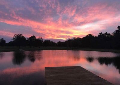 The view of sunset from the dock in front of the C Bar Ranch events barn often will leave you mesmerized. Vivid colors paint the sky, with trees in silhouette in the distance.