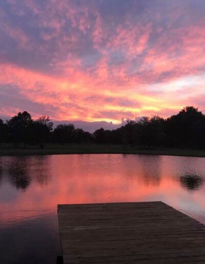 The view of sunset from the dock in front of the C Bar Ranch events barn often will leave you mesmerized. Vivid colors paint the sky, with trees in silhouette in the distance.