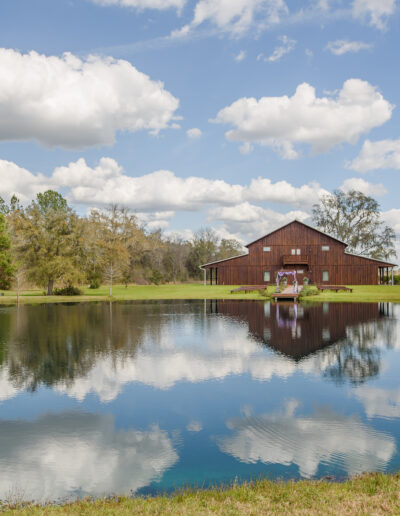 The party barn, trees, and clouds make mirror images in the pond.
