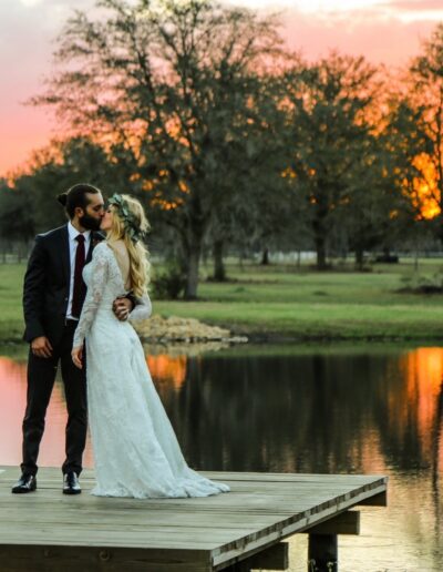 Bride and groom kiss on the C Bar Ranch dock with a brilliant sunset behind them.