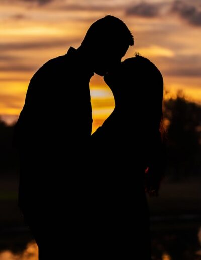 A silhouetted couple kiss in an engagement portrait at sunset at C Bar Ranch.