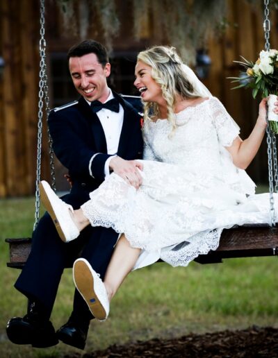 Bride and groom laugh on swing at C Bar Ranch.