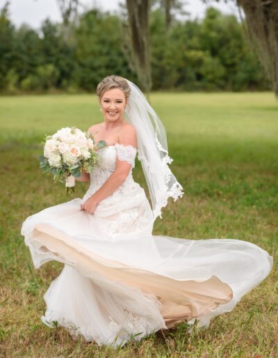 Bride twirls in her dress in a meadow in front of trees at C Bar Ranch.