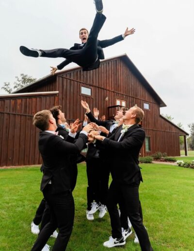 A groom is tossed into the air by his groomsmen at C Bar Ranch.