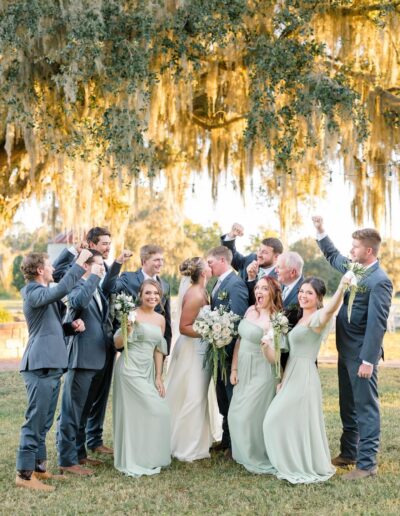 Bride and groom with bridal party under a mossy oak at golden hour at C Bar Ranch.