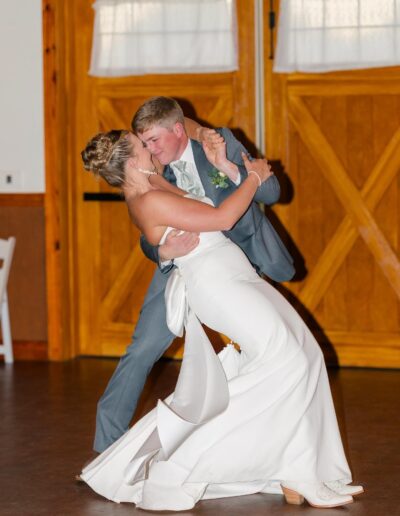 A groom dips his bride as they dance inside the barn at C Bar Ranch.
