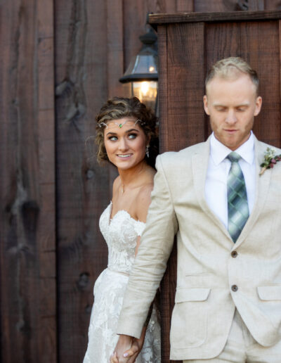 Bride and groom hold hands around a corner before their wedding at C Bar Ranch.