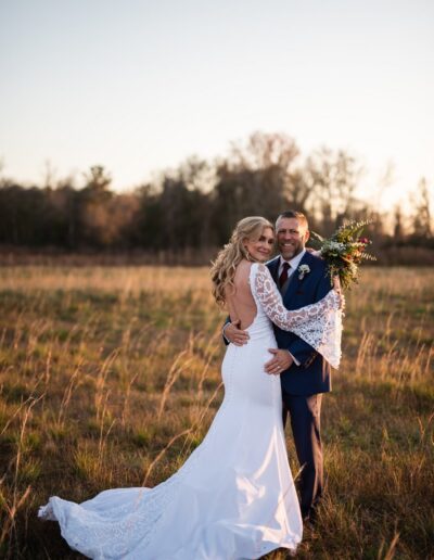 A C Bar Ranch bride and groom pose for a portrait in a field at golden hour.