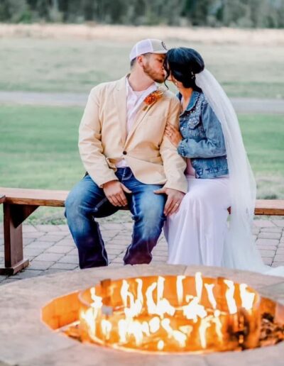 A bride and groom seated at a glowing fire pit on a patio at C Bar Ranch.