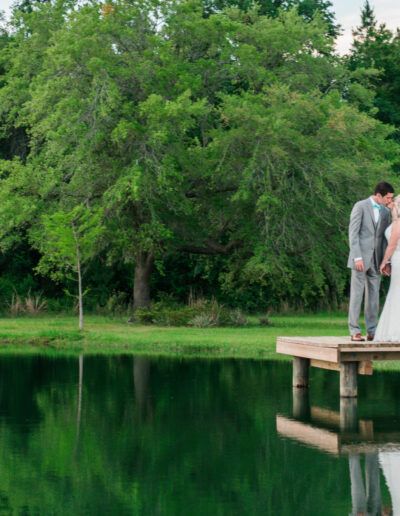 A couple kisses on the dock outside the C Bar Ranch luxury barn.